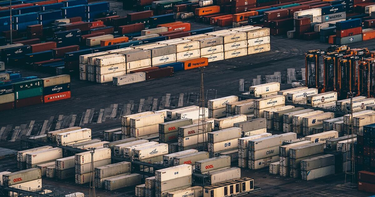 Rows of shipping containers stacked in a port terminal yard at dusk