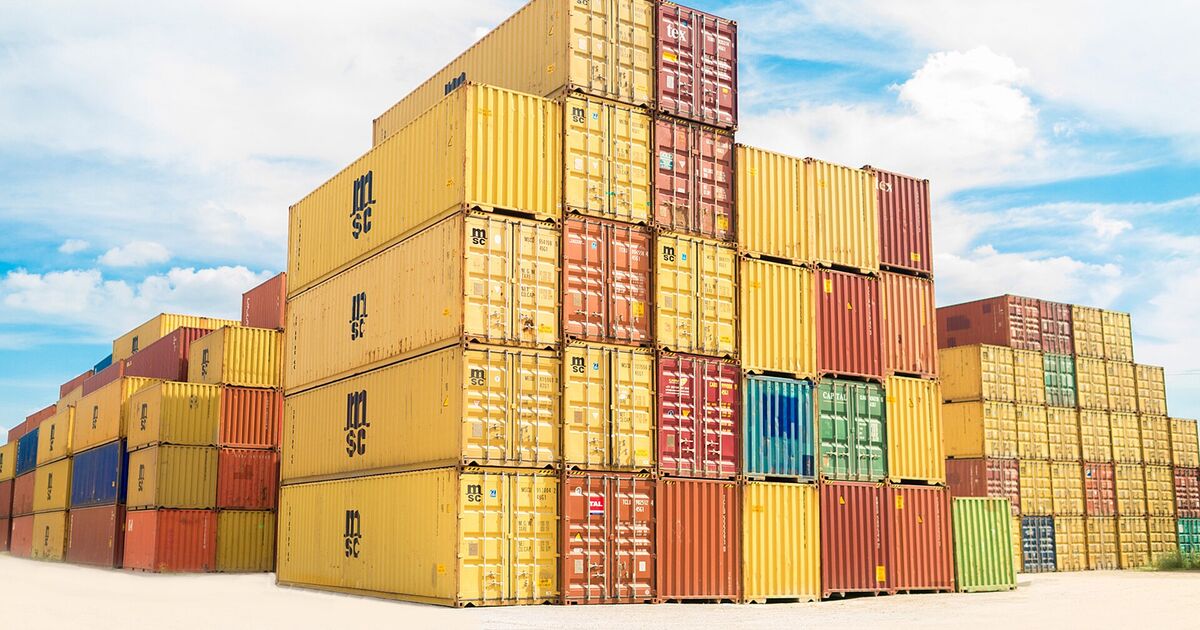 Stack of yellow and red shipping containers against a blue sky
