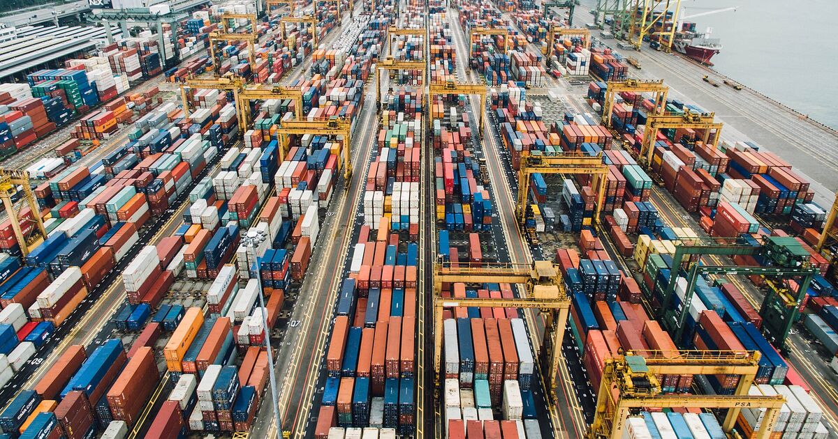 Aerial view of a large container port with rows of stacked boxes and yard cranes